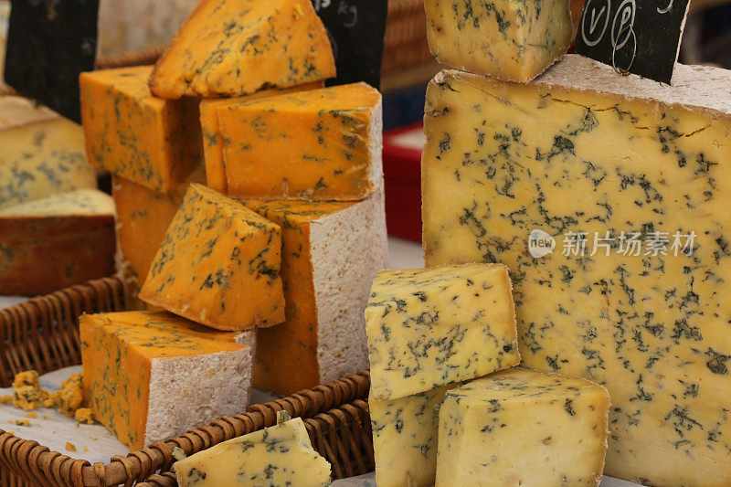 美食乳制品市场的图片，大块的斯蒂尔顿奶酪/软脆的，奶油白色的蓝色奶酪块和方块，样品，品尝和测试在篮子里，用青霉菌roqueforti模具/霉菌制成的蓝色静脉，就像Roquefort / Gorgonzola